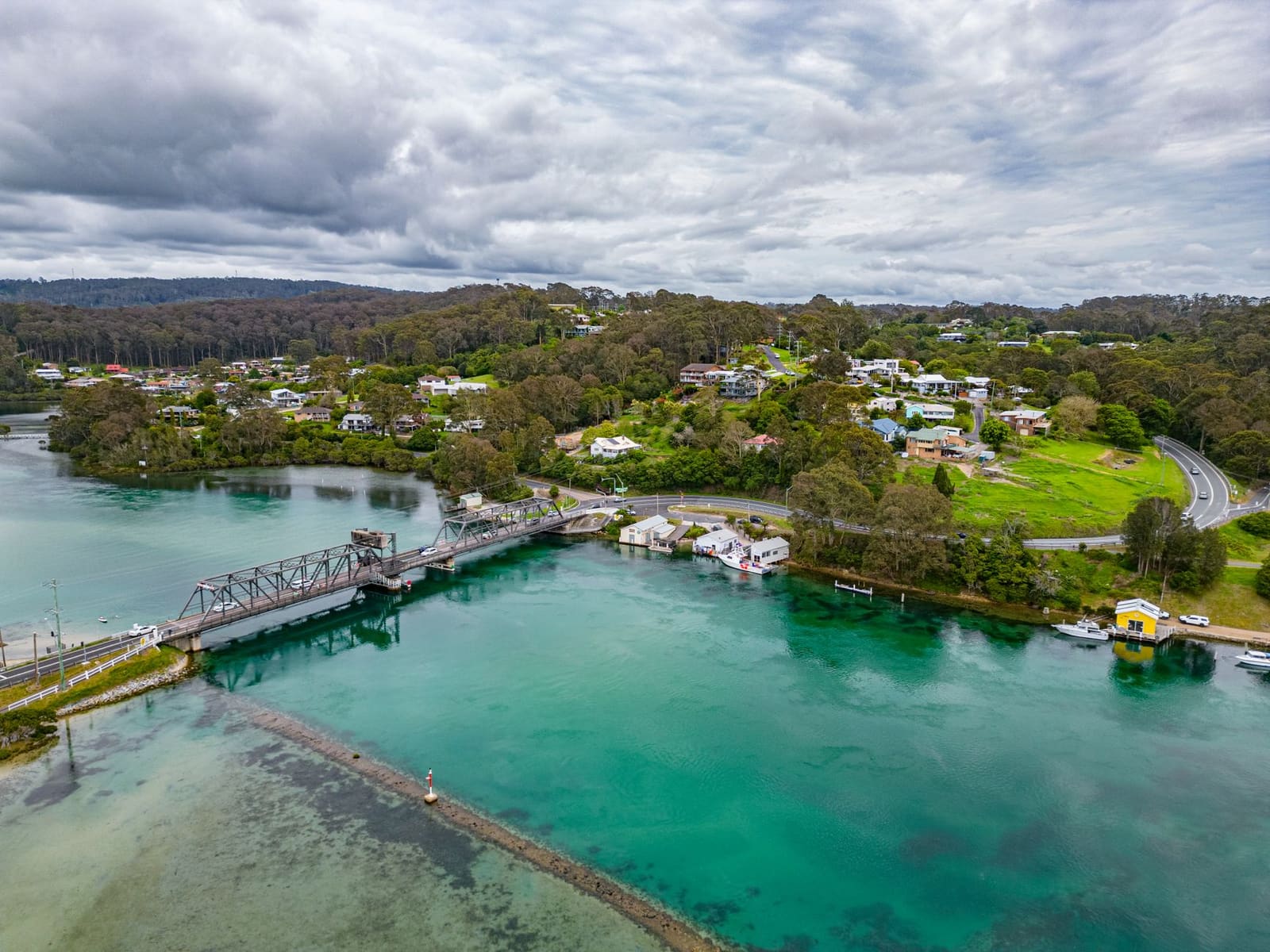 An inlet and bridge on the South Coast, with boats moored along the shore.